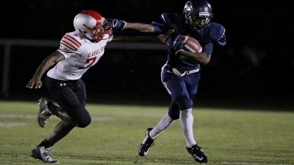 
Columbus’ Ivan Smith (2) stiff-arms Coral Gables’ Kemontae Paulk (24) at Tropical Park in Miami on Nov. 20, 2014.
