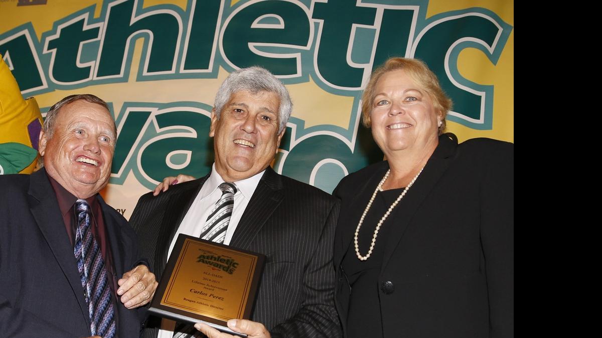 
Ronald Reagan High athletic director Carlos Perez, center, is presented the 2015 All-Dade Lifetime Achievement Award by Bill Van Smith, left, and GMAC executive secretary Cheryl Golden during the All-Dade Athletic Awards at Jungle Island on Wednesday, May 20, 2015.
