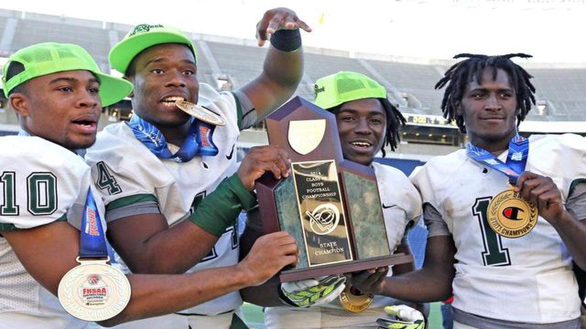 
Miami Central’s Olin Cushion III, Fermin Silva, Anthony Jones , and Da'Vante Phillips , hold the trophy after defeating Armwood for the 2014 Class 6A Boys Football Championship at the Citrus Bowl in Orlando, Florida, December 13, 2014.
