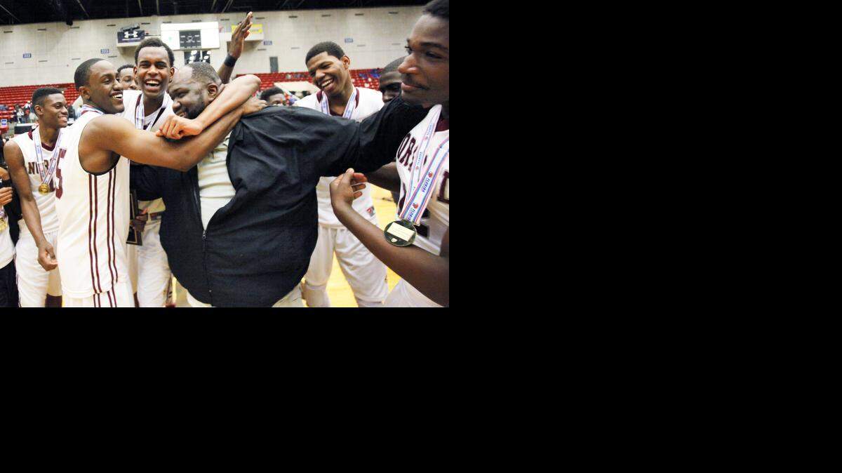 
Norland head coach Lawton Williams is surrounded by his team after winning the state title against Lake Minneola during the FHSAA 6A Basketball Championship Saturday March 1, 2014 in Lakeland, Florida. 
