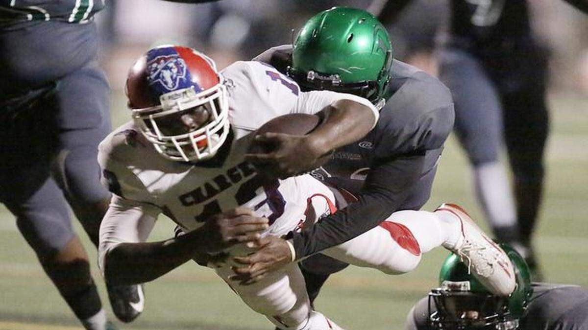 
North Miami Pioneers linebacker Jonathan Jeune (30) takes down North Miami Beach Chargers’ Cedric Wiggins (13) during their football game Thursday, Oct. 2, 2014, at North Miami Stadium.
