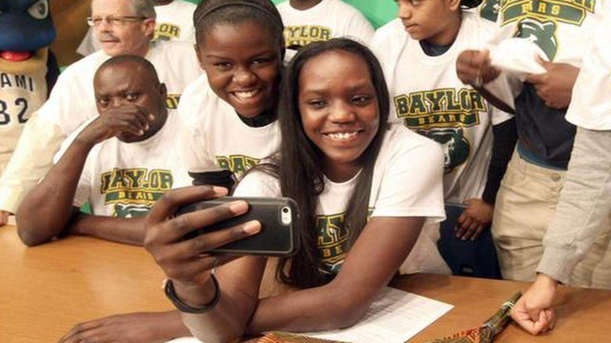 
Miami High basketball player Beatrice Mompremier, center, takes a selfie after signing with Baylor University on Tuesday, Nov. 18, 2014. 
