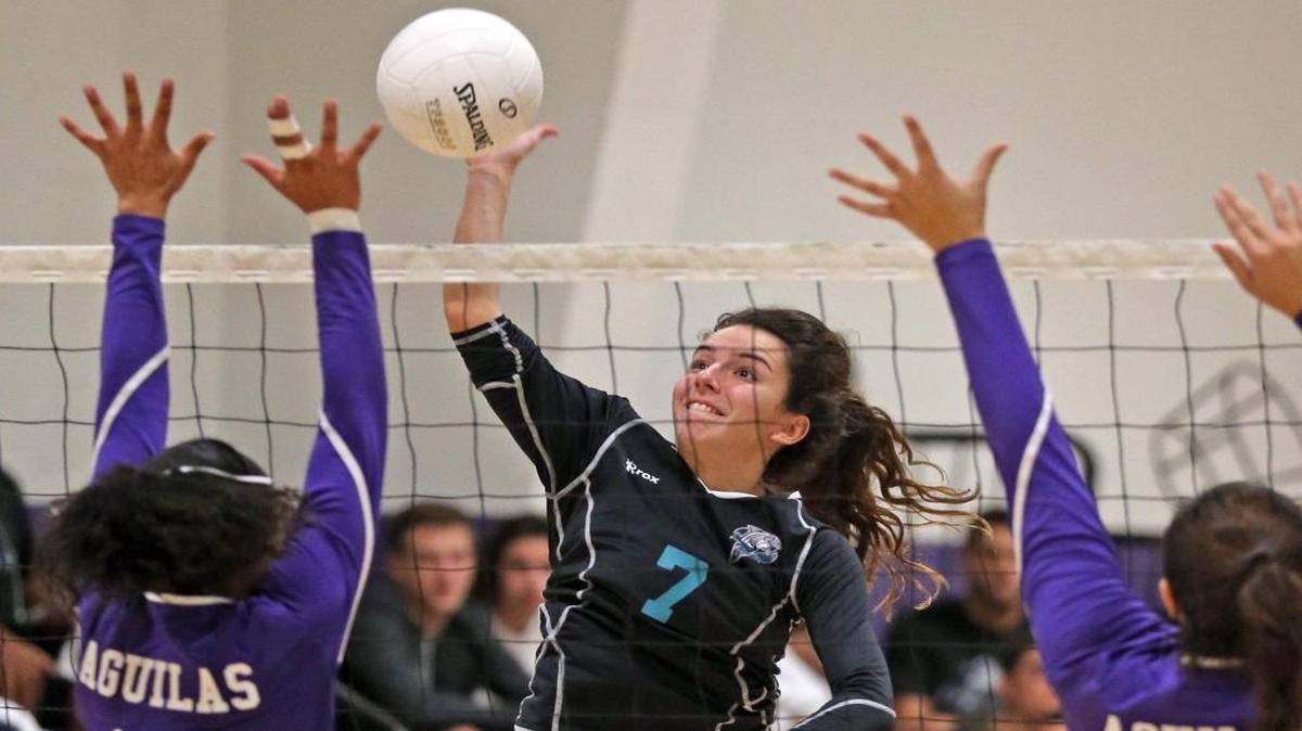 Coral Reef’s Maria Asecio hits the ball as Southwest’s Mya Thomas, left, and Jocelyn Garcia defend Tuesday night.