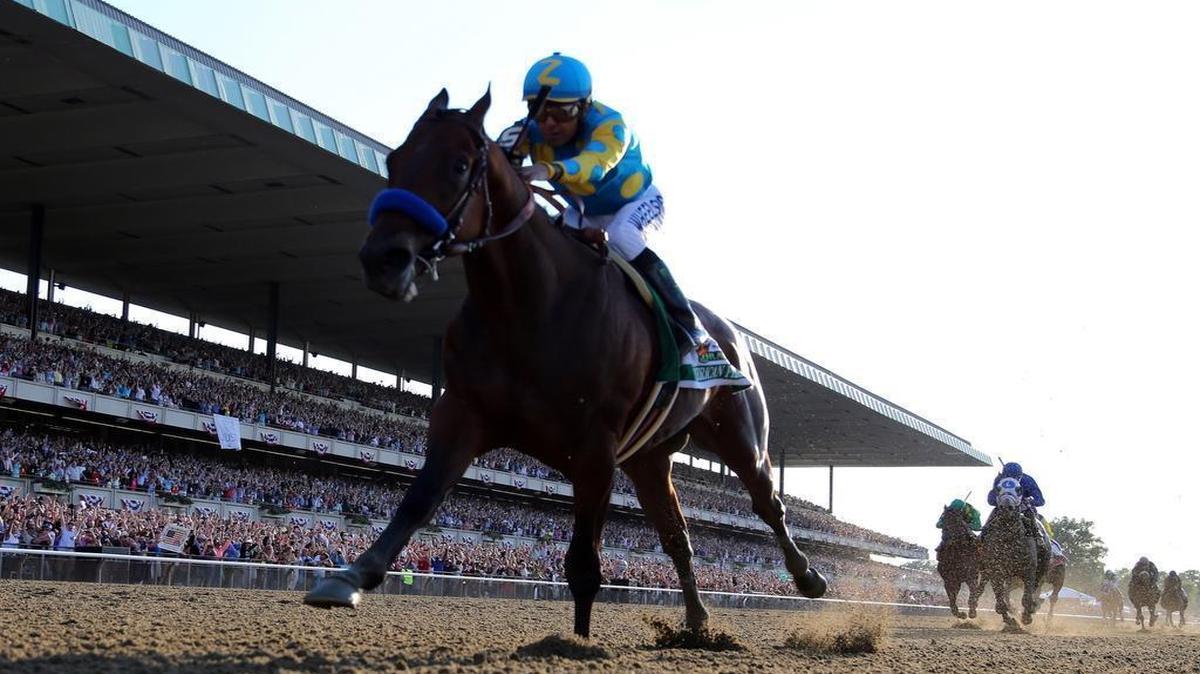 
American Pharoah #5, ridden by Victor Espinoza, comes down the final stretch ahead of the field on his way to winning the 147th running of the Belmont Stakes at Belmont Park on June 6, 2015 in Elmont, New York. 
