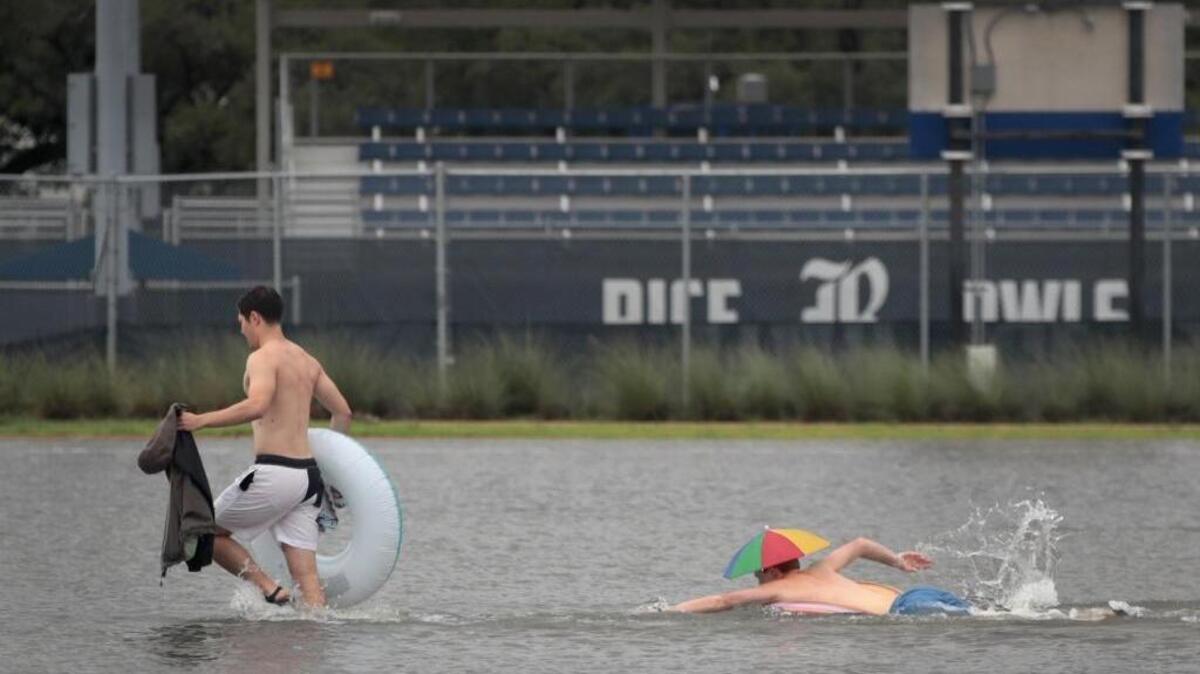 Riley Gardell and Jacob Song make their way across a flooded parking lot on the campus of Rice University in Houston after it was inundated with water from Hurricane Harvey on Sunday afternoon.