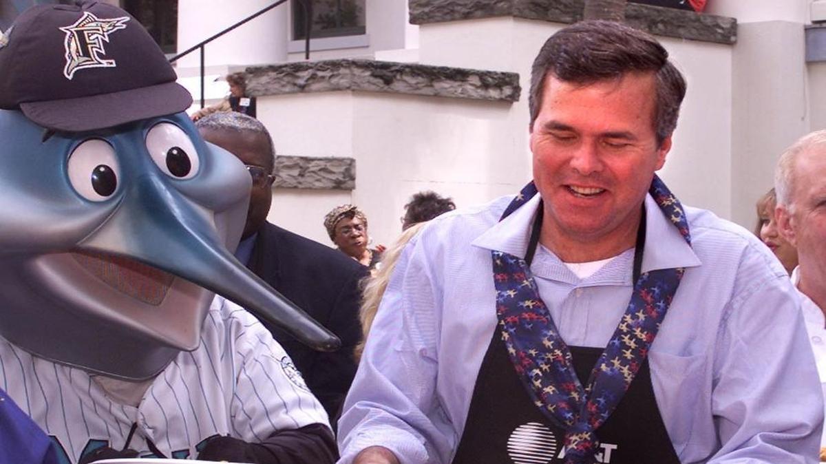File photo: Gov. Jeb Bush, right, serves up a plate of paella with Billy, the Marlins’ mascot, during Dade County Days on Thursday, April 5, 2001, in Tallahasssee, Fla.