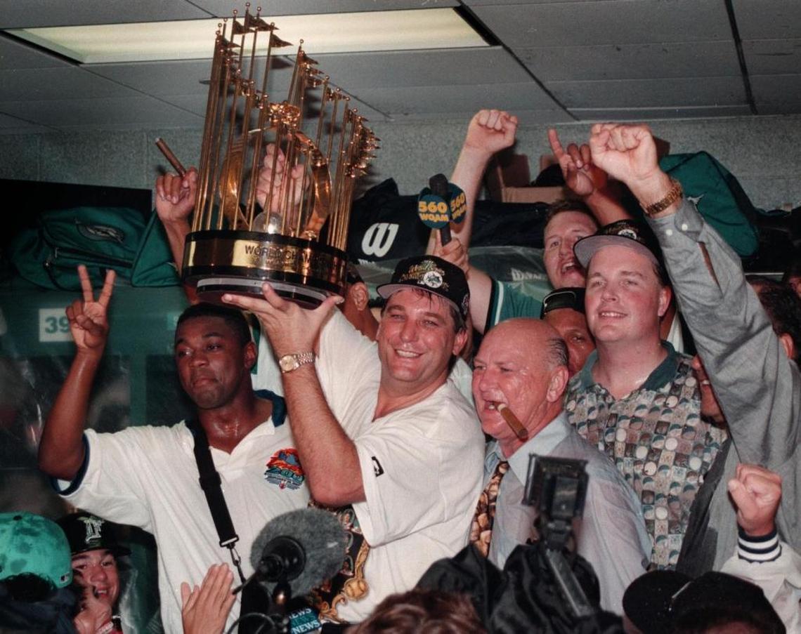 Don Smiley hoists the Championship trophy in the Marlins locker room after the Marlins defeated the Cleveland Indians in Game 7 of the 1997 World Series. To his right with a cigar in his mouth is club owner H. Wayne Huizenga.