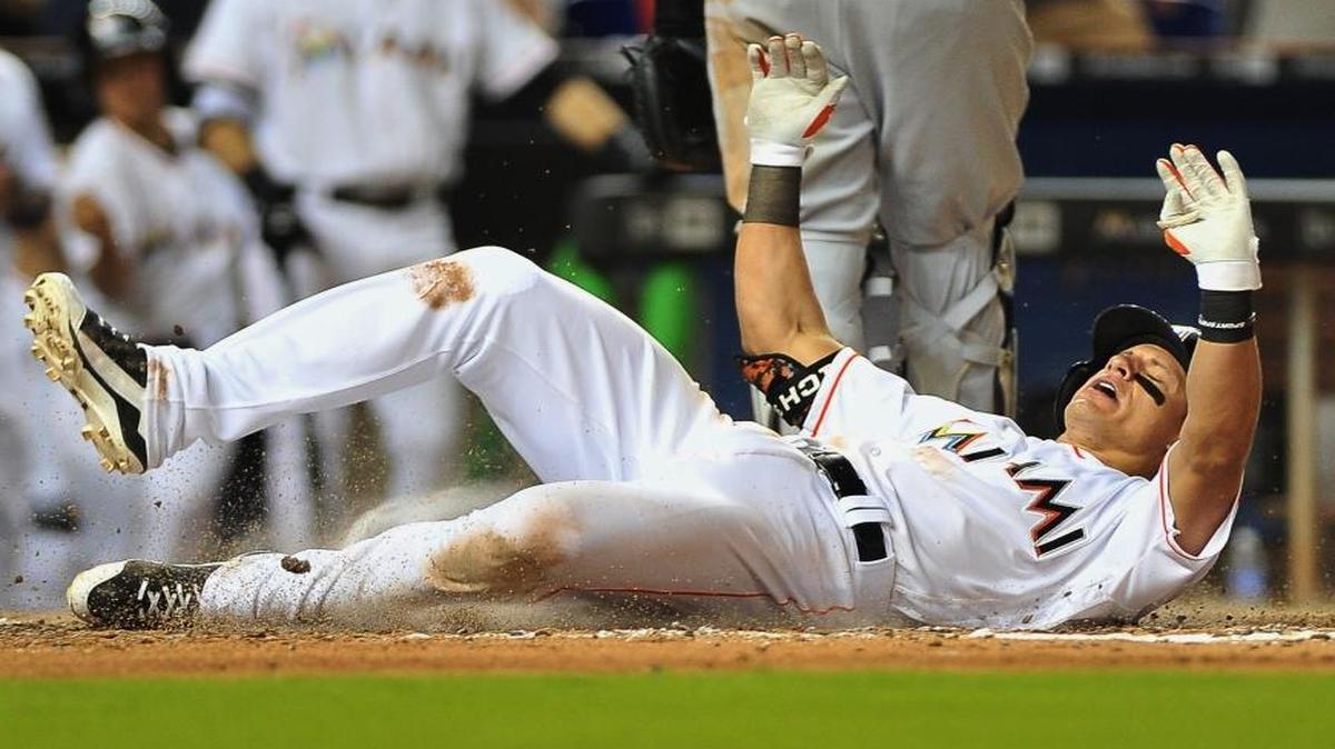 Miami Marlins Derek Dietrich slides into home on a throwing error after hitting a triple in the seventh inning of a baseball game against the Milwaukee Brewers, Mon., May 9, 2016, in Miami.