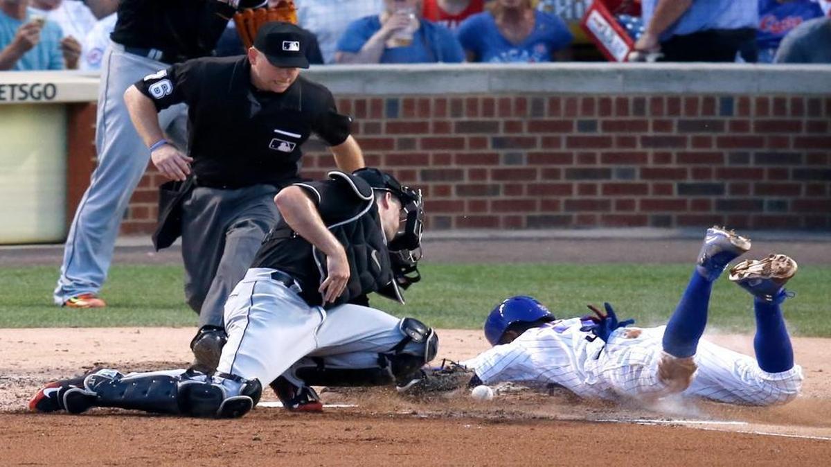 Chicago Cubs' Dexter Fowler, right, scores past Miami Marlins catcher J.T. Realmuto, as umpire Mike Muchlinski watches during the third inning of a baseball game Tues., Aug. 2, 2016, in Chicago.