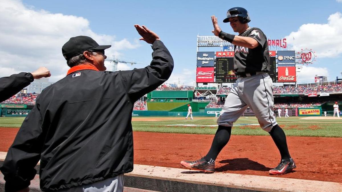 Miami Marlins manager Don Mattingly, left, prepares to celebrate with J.T. Realmuto, after he and Adeiny Hechavarria scored, on an error by Washington Nationals second baseman Stephen Drew, during the third inning of a baseball game at Nationals Park, Sun., May 15, 2016, in Washington.