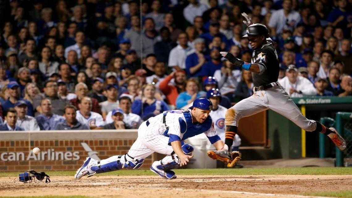 Miami Marlins' Dee Gordon, right, scores after Chicago Cubs catcher Miguel Montero was unable to field a throw by Anthony Rizzo during the seventh inning of a baseball game Wed., June 7, 2017, in Chicago.