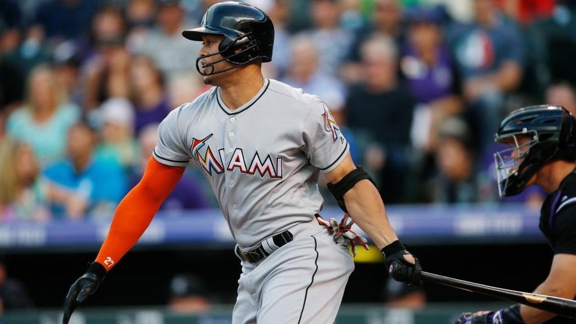 Miami Marlins' Giancarlo Stanton hits into a force play but drives in a runner from third base on a pitch from Colorado Rockies starting pitcher Chad Bettis in the first inning of a baseball game Saturday, Aug. 6, 2016, in Denver.
