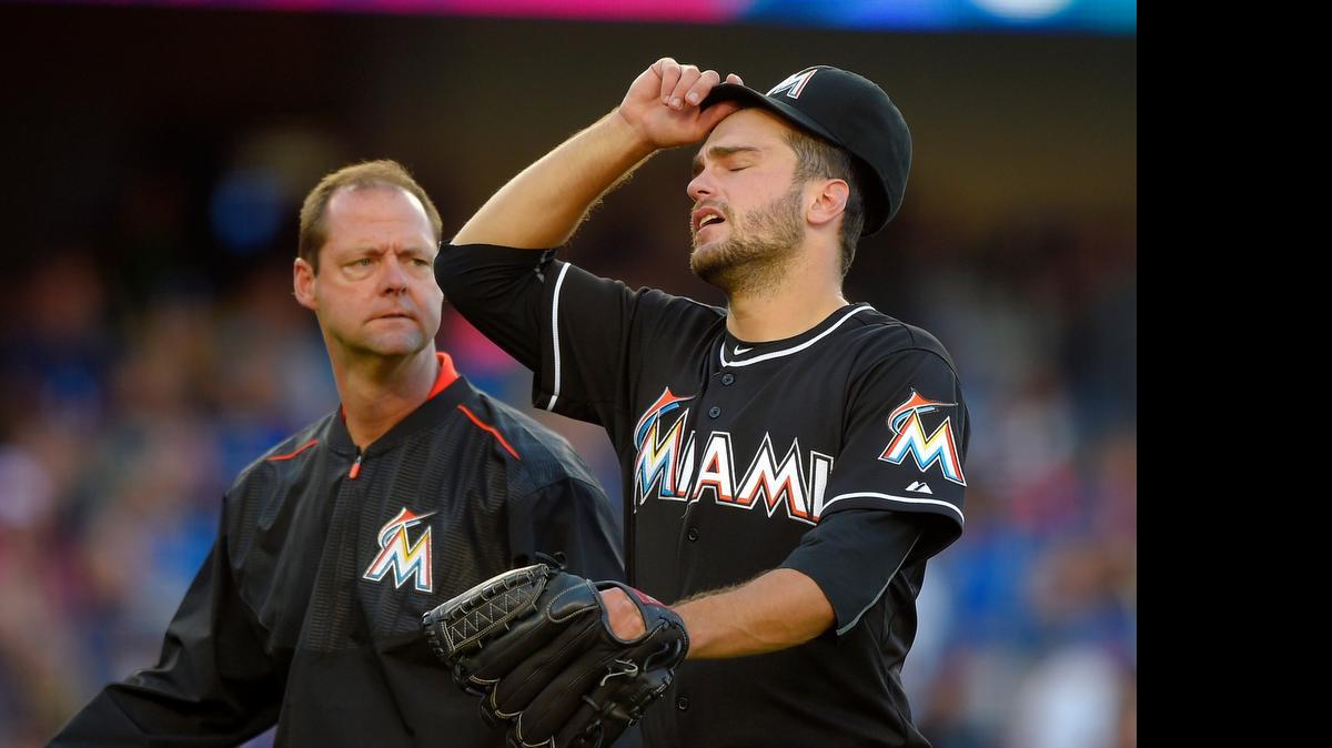 
Miami Marlins pitcher Jarred Cosart, right, walks off the field with a trainer after being taken out of the game during the sixth inning Wednesday, May 13, 2015, in Los Angeles.
