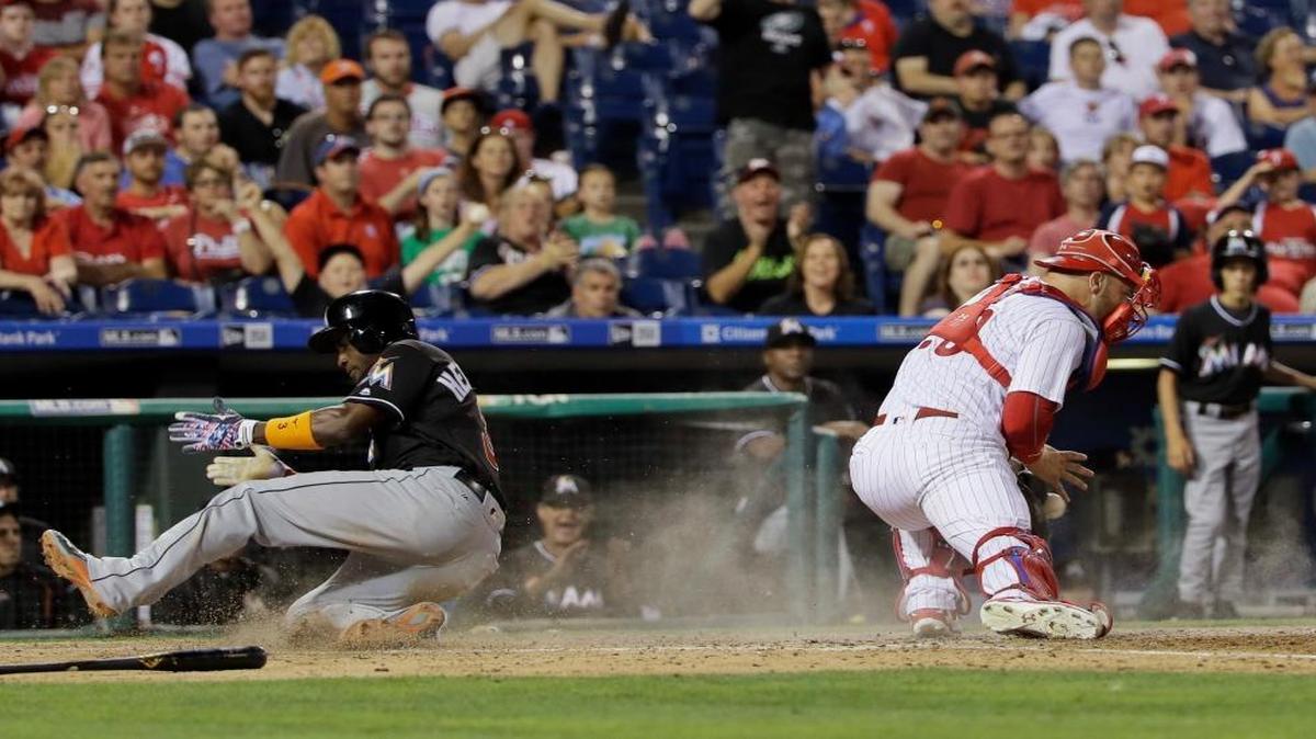 Miami Marlins' Adeiny Hechavarria, left, scores past Philadelphia Phillies catcher Cameron Rupp on the go-ahead RBI-single by Christian Yelich during the 11th inning of a baseball game, Tues., July 19, 2016, in Philadelphia. Miami won 2-1 in 11 innings.