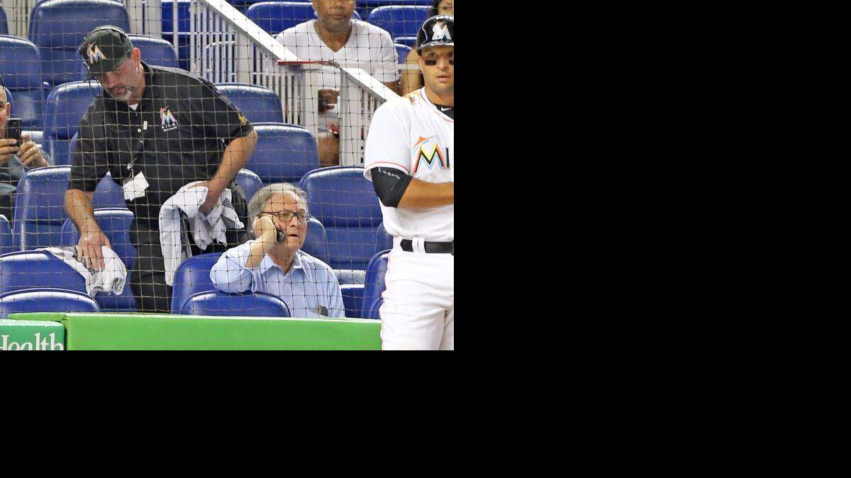 
Miami Marlins owner Jeffrey Loria talks on the phone as a stadium worker wipes a seat dry after rain delayed the game and the roof was closed as the Marlins play the Atlanta Braves on opening day at Marlins Park in Miami, Florida, April 6, 2015.
