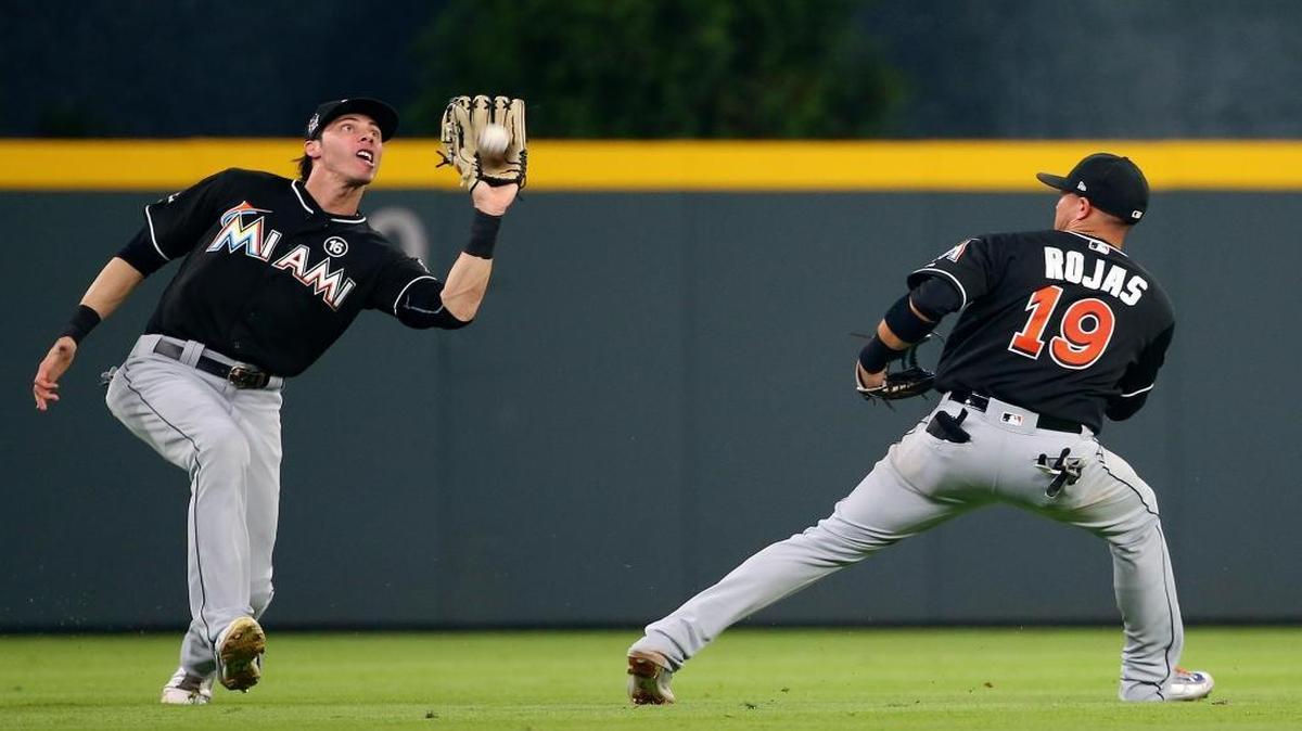 Miami Marlins center fielder Christian Yelich, left, catches a fly ball from Atlanta Braves' Kurt Suzuki as shortstop Miguel Rojas (19) backs away in the sixth inning of a baseball game Saturday, Aug. 5, 2017, in Atlanta.