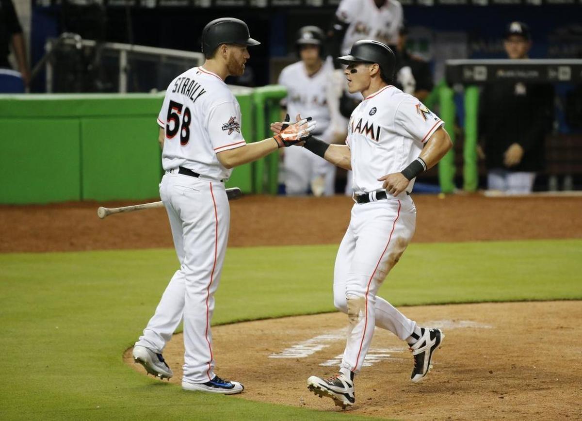 Miami Marlins third baseman Derek Dietrich (32) is greeted by Miami Marlins bench coach Dan Straily (58) after scoring on a sacrifice fly hit by shortstop JT Riddle (39) in the 6th inning as the Marlins play host to the St. Louis Cardinals at Marlins Park on Tues., May 9, 2017.