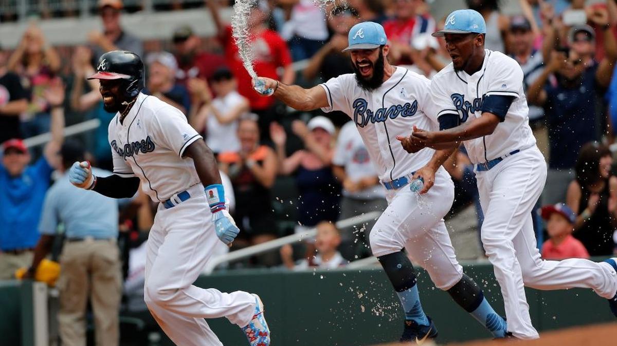 Atlanta’s Brandon Phillips, left, is chased by teammates Jose Ramirez and Julio Teheran after he drove in the winning run to beat the Miami Marlins on Sunday afternoon.