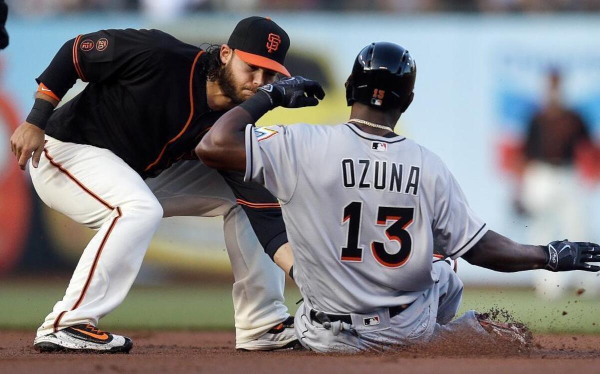 San Francisco Giants' Brandon Crawford, left, tags out Miami Marlins' Marcell Ozuna (13) on an attempted steal of second base during the first inning of a baseball game Saturday, April 23, 2016, in San Francisco.