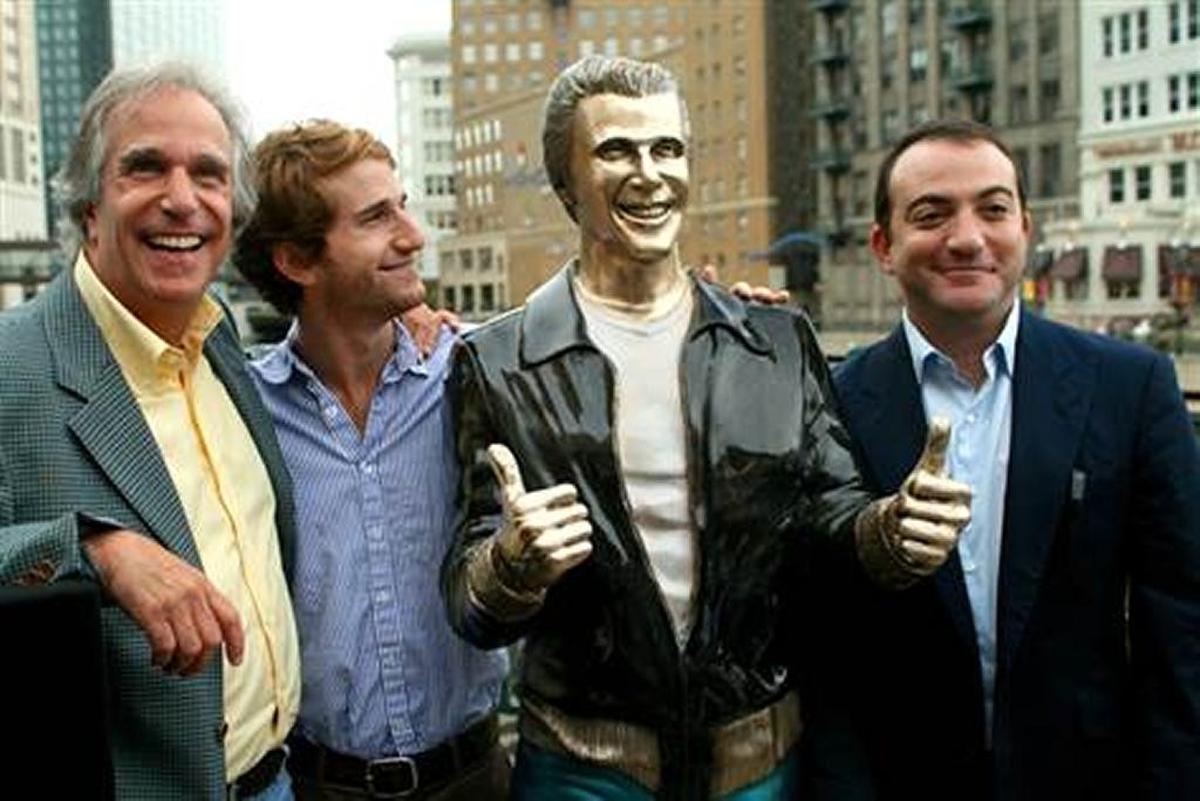 Actor Henry Winkler, left, poses with his sons Max Winkler, second left, and Jed Weitzman as they stand with a bronze statue of the "Happy Days" character Arthur Fonzarelli, also known as "The Fonz,"