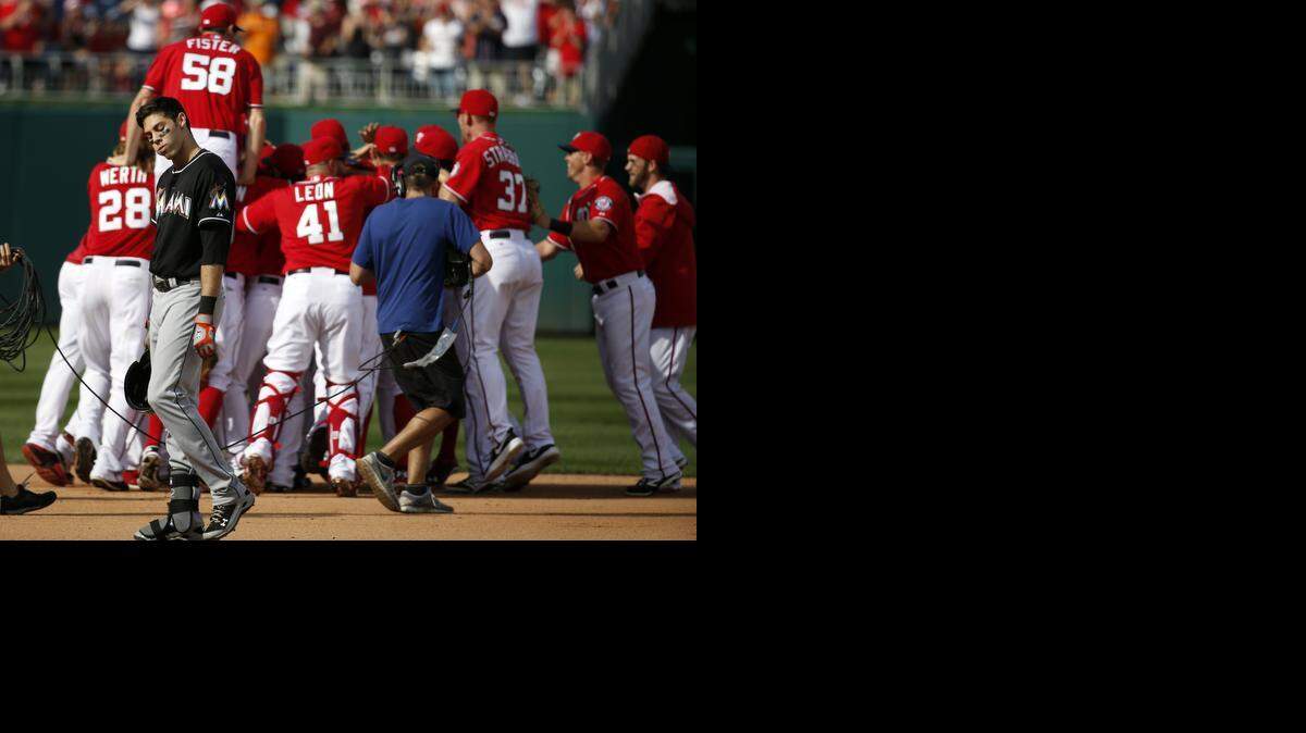 
Miami Marlins' Christian Yelich (21) walks to the dugout after making the last out as the Washington Nationals celebrate with starting pitcher Jordan Zimmermann after a baseball game at Nationals Park, Sunday, Sept. 28, 2014, in Washington. Zimmermann pitched an no-hitter, and the Nationals won 1-0. 
