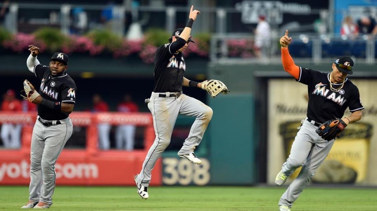 From left, Miami Marlins' Marcell Ozuna, Christian Yelich and Giancarlo Stanton celebrate in the outfield after a victory against the Philadelphia Phillies in the first baseball game of a doubleheader, Tuesday, Aug. 22, 2017, in Philadelphia. The Marlins won 12-8.