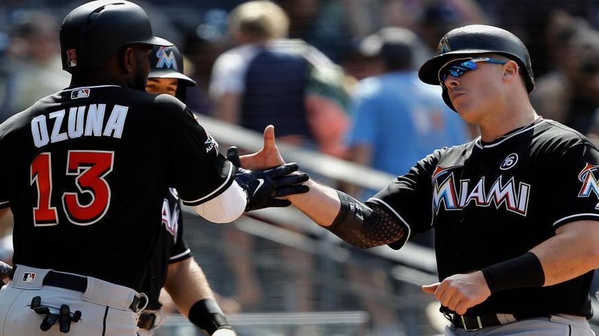 Miami Marlins' Marcell Ozuna, left, and J.T. Realmuto, obscured second from left, congratulate Justin Bour, right, at the plate for Bour's three-run home run against the San Diego Padres during the sixth inning of a baseball game in San Diego, Sunday, April 23, 2017.