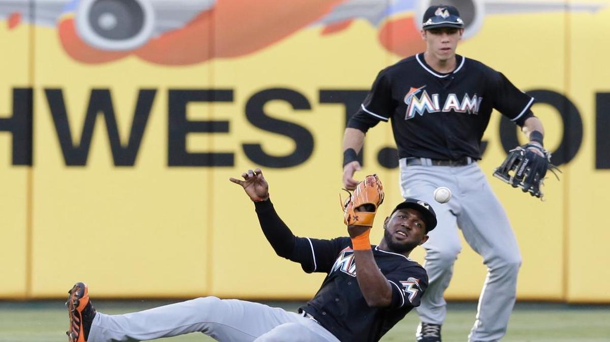 
Miami Marlins center fielder Marcell Ozuna (13) can't handle the hit in front of teammate left fielder Christian Yelich giving up a single to Texas Rangers Alex Rios during the second inning of a baseball game in Arlington, Texas, Tuesday, June 10, 2014. 
