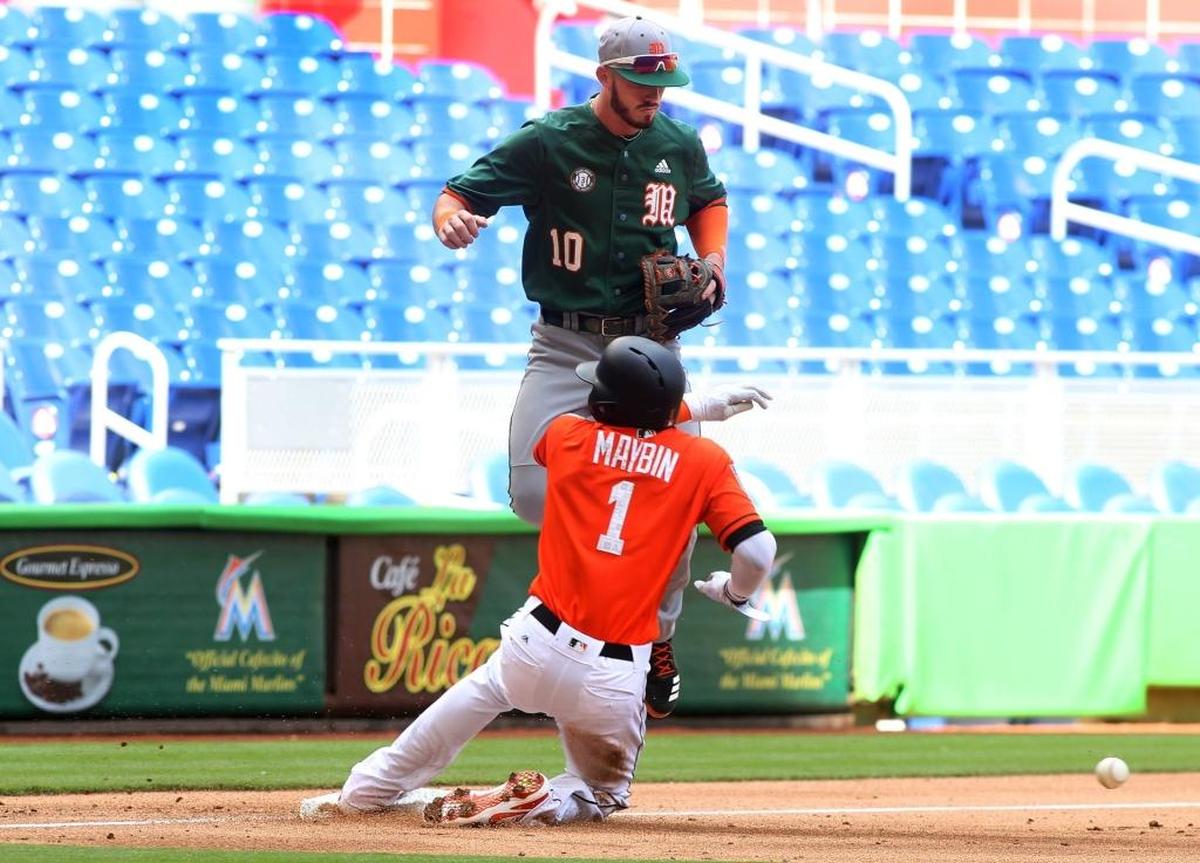Miami Marlins outfielder Cameron Maybin slides safely into third bases as University of Miami Hurricanes third baseman Romy Gonzalez jumps during the first inning of a exhibition baseball game at Marlins Park on Tues., March 27, 2018 in Miami.