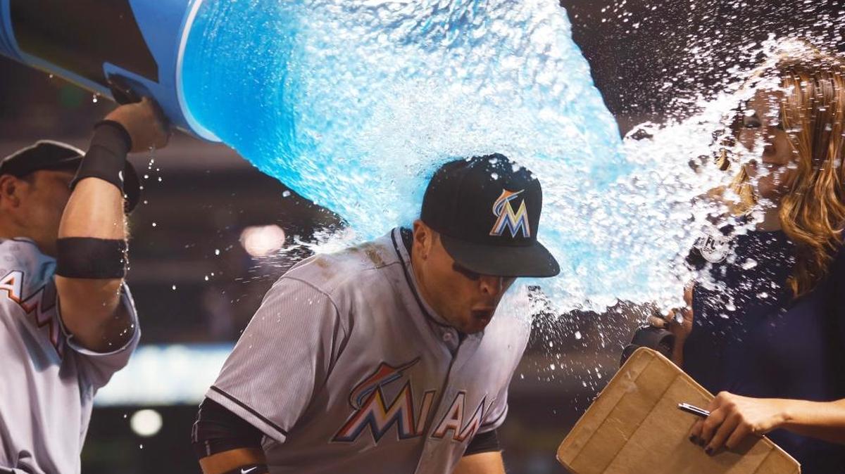 Miami Marlins third baseman Martin Prado is doused by Miguel Rojas, left, during an interview, after the Marlins' 5-3 victory over the Colorado Rockies in a baseball game Fri., Aug. 5, 2016 in Denver. Prado hit a two-run single off Colorado Rockies relief pitcher Carlos Estevez in the ninth inning.