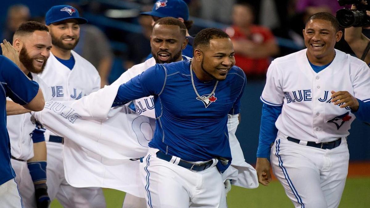 
Toronto Blue Jays DH Edwin Enacarnacion, center, gets his jersey ripped off after hitting a walk-off two-run home run to defeat the Miami Marlins during ninth inning in Toronto on Tuesday, June 9, 2015.
