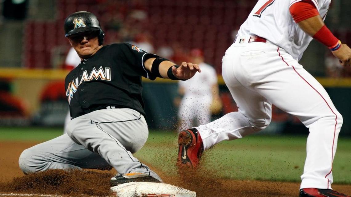 Miami Marlins' Miguel Rojas, left slides safely into third on a wild pitch as Cincinnati Reds third baseman Eugenio Suarez (7) takes the throw during the eighth inning of a baseball game, Mon., Aug. 15, 2016, in Cincinnati.