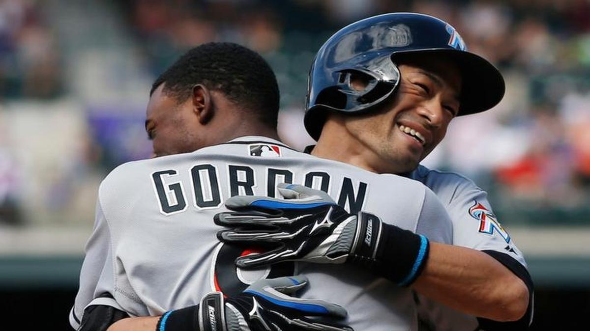 Miami Marlins' Dee Gordon, front, hugs Ichiro Suzuki after Suzuki tripled off Colorado Rockies relief pitcher Chris Rusin in the seventh inning of a baseball game Sunday, Aug. 7, 2016 in Denver. The hit was the 3,000th in Suzuki's major League career.