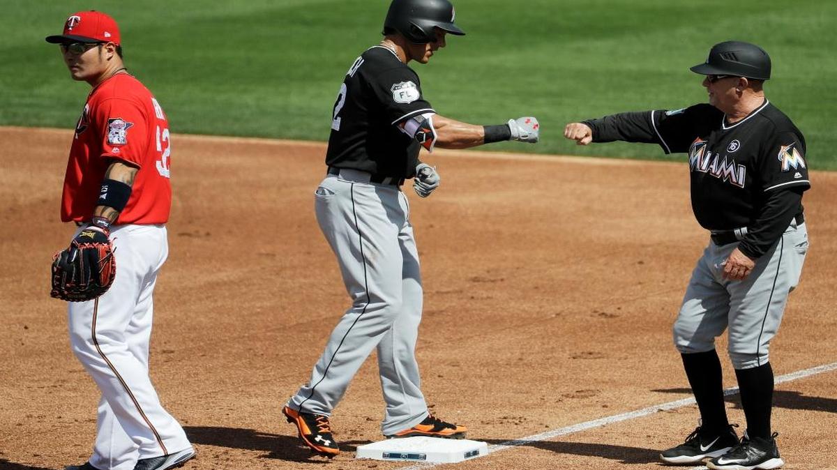 Miami Marlins' Derek Dietrich, center, fist-bumps first base coach Perry Hill after hitting a single in the first inning of an exhibition spring training baseball game against the Minnesota Twins in Fort Myers, Fla., Mon., Feb. 27, 2017.
