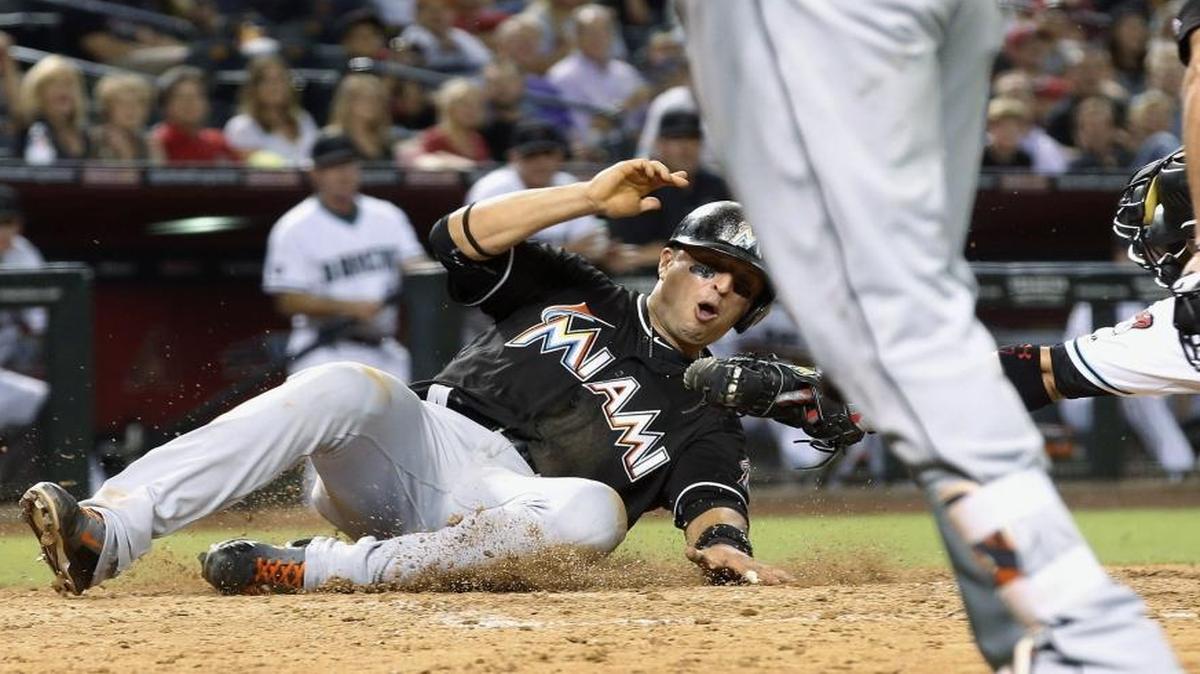 Miami Marlins' Martin Prado, left, eludes the tag of Arizona Diamondbacks' Welington Castillo, back right, to score a run during the seventh inning of a baseball game Fri., June 10, 2016, in Phoenix.