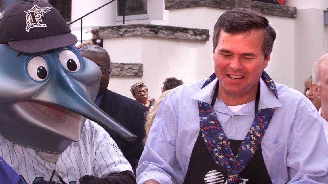 Former Florida Gov. Jeb Bush, right, serves up a plate of paella with Billy, the Florida Marlins' mascot, during Dade County Days at the Capitol in this Thursday, April 5, 2001, file photo taken in Tallahasssee, Fla. The Miami Marlins are for sale, and former Florida Gov. Jeb Bush and former Yankees star Derek Jeter are interested in buying them, according to a published report.