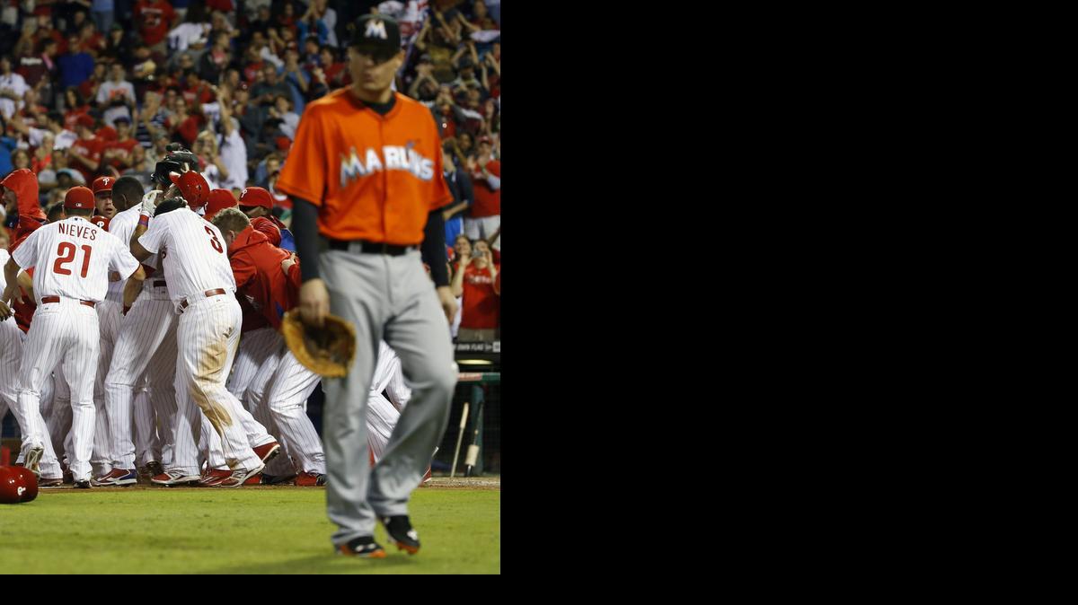 
Philadelphia Phillies players celebrate after Cody Asche's game-winning two-run home run as Miami Marlins first baseman Jeff Baker, right, walks off the field during the 10th inning of a baseball game, Friday, Sept. 12, 2014, in Philadelphia. Philadelphia won 3-1 in 10 innings. 
