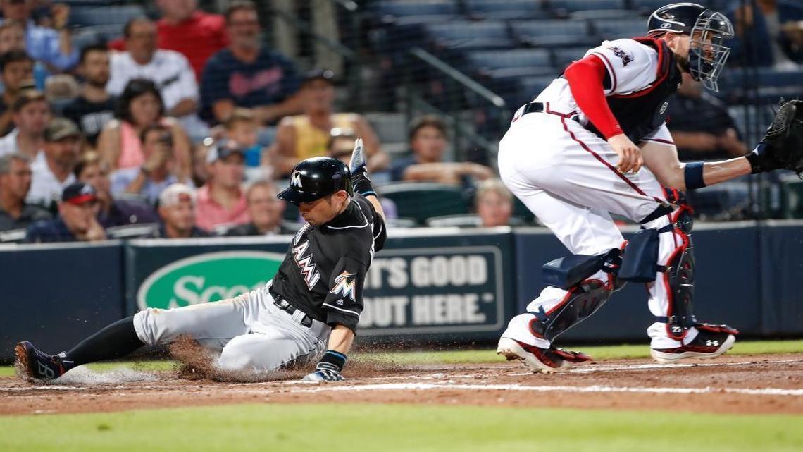 Miami Marlins' Ichiro Suzuki (51) scores ahead of the throw to Atlanta Braves catcher Tyler Flowers on a two-run double by Christian Yelich in the third inning of a baseball game, Tues., Sept. 13, 2016, in Atlanta.