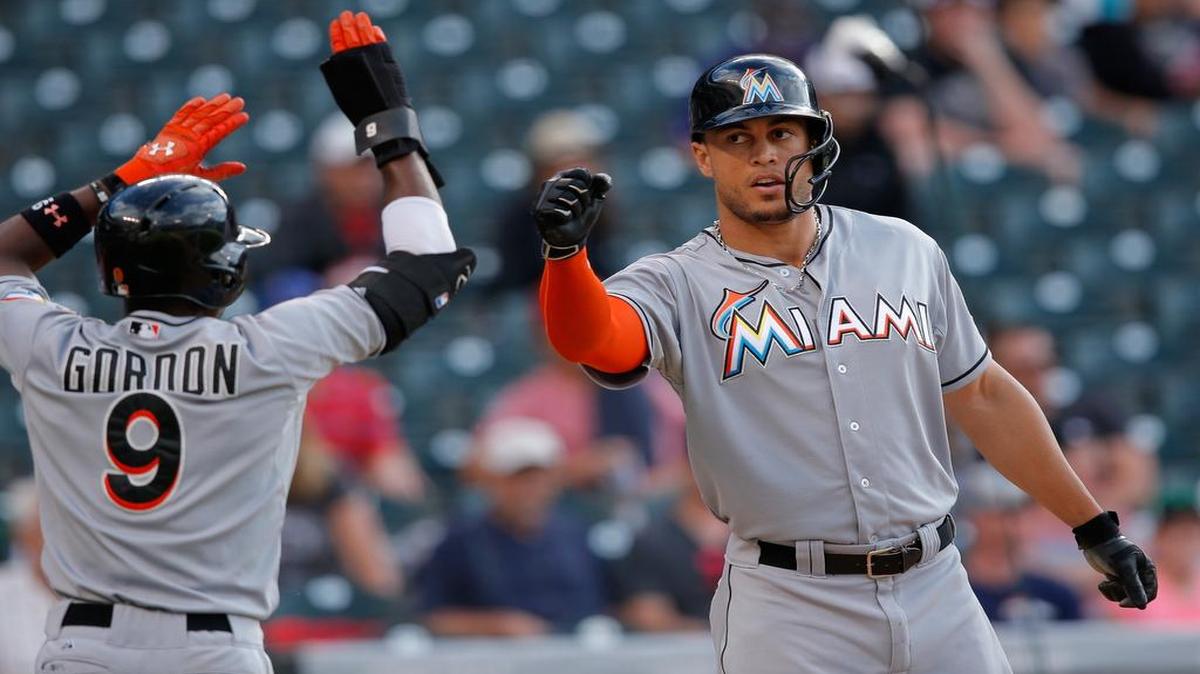
Dee Gordon #9 and Giancarlo Stanton #27 of the Miami Marlins celebrate after scoring on a single by Jeff Baker #10 of the Miami Marlins as the Colorado Rockies held a 10-5 lead in the ninth inning at Coors Field on June 6, 2015 in Denver, Colorado. 
