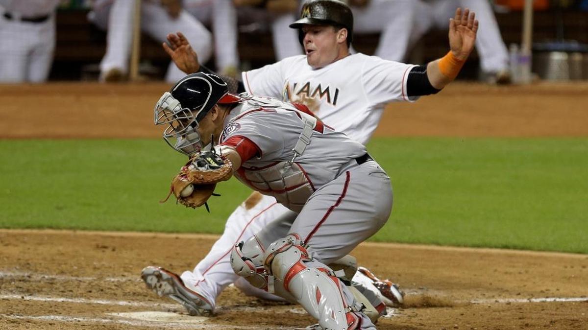 Miami Marlins' Justin Bour slides safely into home plate as Washington Nationals catcher Wilson Ramos is late on the tag in the sixth inning of a baseball game, Mon., Sept. 19, 2016, in Miami. The Marlins won 4-3.