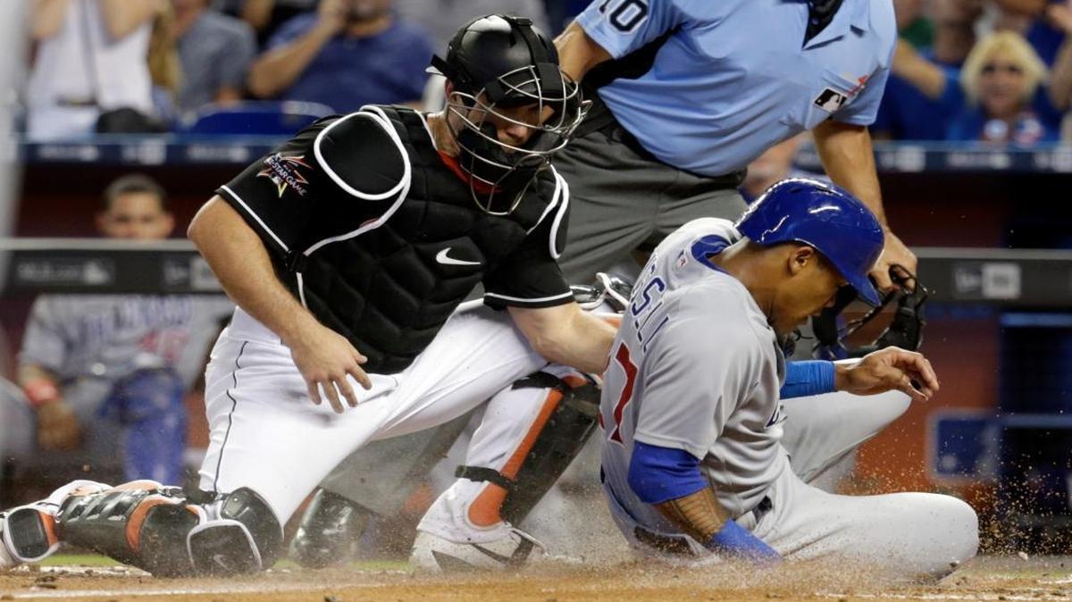 Chicago Cubs' Addison Russell, right, scores past Miami Marlins catcher J.T. Realmuto on a single by Javier Baez during the fourth inning of a baseball game, Saturday, June 24, 2017, in Miami.