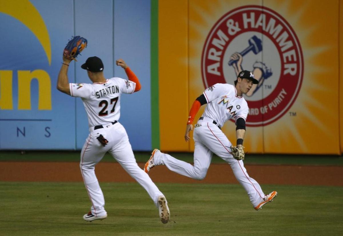 Miami Marlins center fielder Christian Yelich makes a catch on a fly ball by New York Mets catcher Rene Rivera as Giancarlo Stanton almost collide during the second inning of a baseball game at Marlins Park on Thurs., June 29, 2017 in Miami.