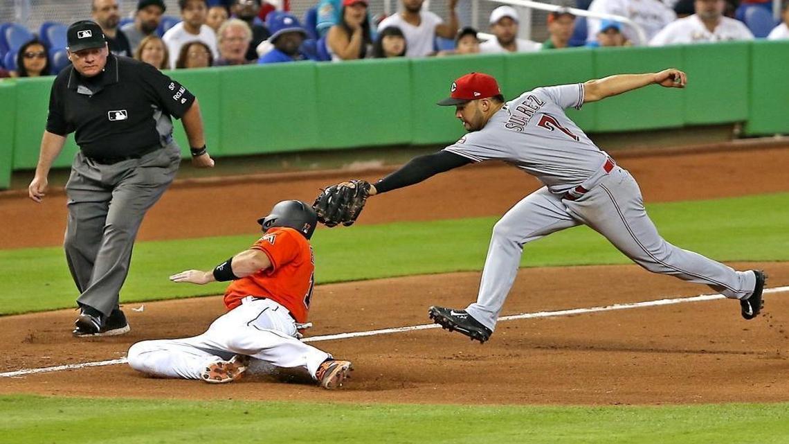 The Marlins' A.J. Ellis (17) is tagged out at third base by Cincinnati's Eugenio Suarez in the sixth inning as the Mami Marlins host the Cincinnati Reds on Sunday, July 30, 2017.