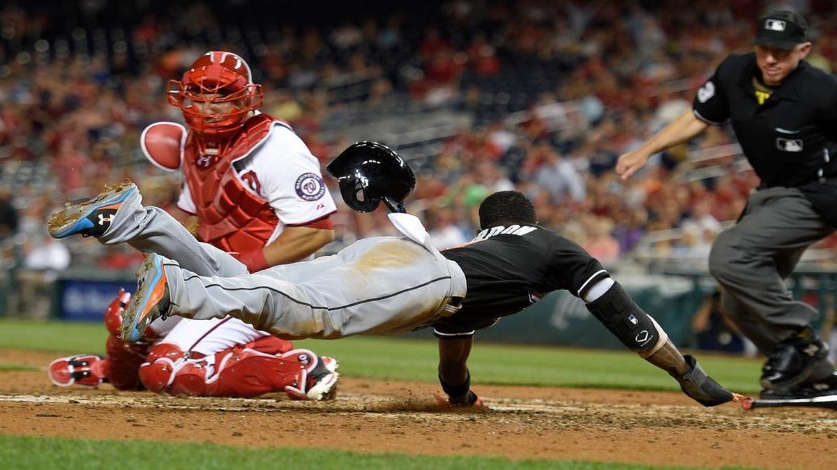 
The Marlins' Dee Gordon dives to score on a Jeff Baker single against Nationals catcher Wilson Ramos during the eighth inning Monday night. The run gave Miami a short-lived lead in the opener of a three-game series in Washington.
