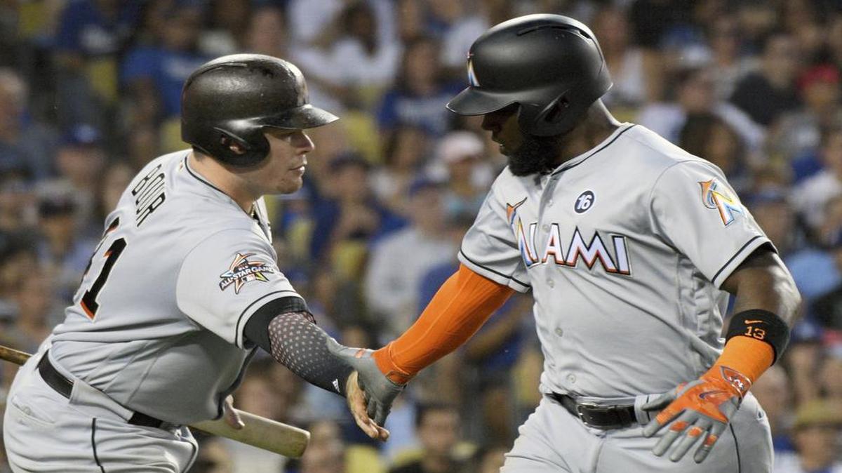 Miami Marlins' Marcell Ozuna, right, slaps hands with Justin Bour after scoring on a double by Giancarlo Stanton against the Los Angeles Dodgers in the third inning of a baseball game in Los Angeles, Saturday, May 20, 2017.
