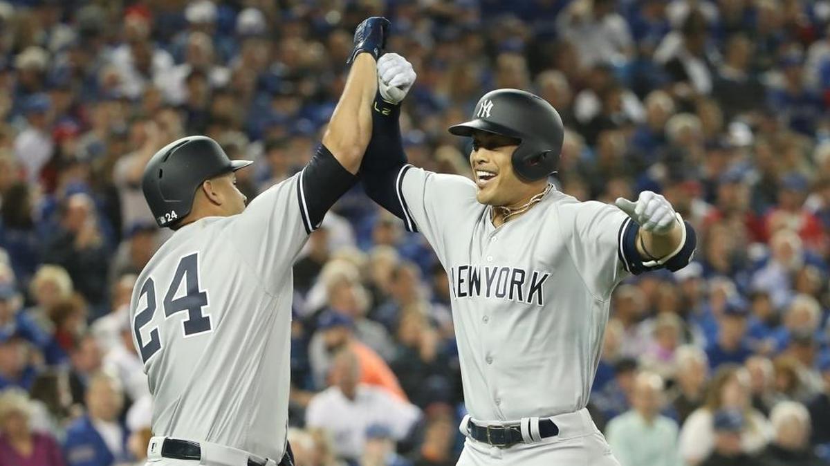 Giancarlo Stanton #27 of the New York Yankees is congratulated by Gary Sanchez #24 after hitting a two-run home run in the first inning on Opening Day during MLB game action against the Toronto Blue Jays at Rogers Centre on March 29, 2018 in Toronto, Canada.