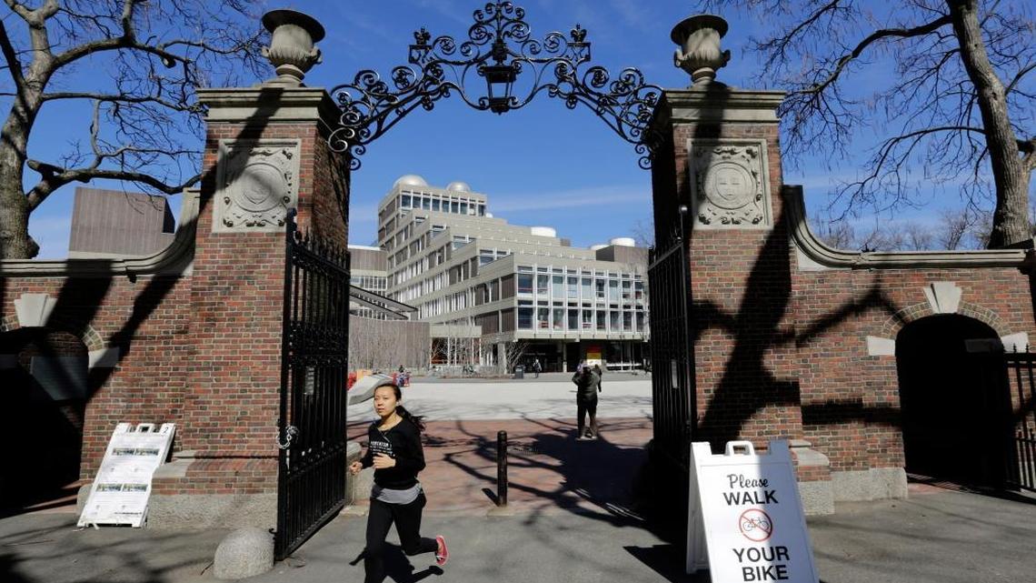 In this Sunday, March 13, 2016 photo, a woman passes through a gate on the campus of Harvard University, in Cambridge, Mass.Harvard University canceled the remaining two games of the 2016 men’s soccer season following an investigation into reports of a tradition of male players keeping an annual “Scouting Report” ranking female soccer players’ physical attributes and perceived sexual appeal.
