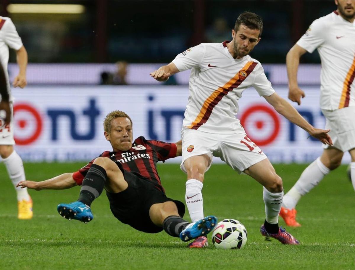 AC Milan's Keisuke Honda, left, challenges Roma's Miralem Pjanic during a Serie A soccer match between AC Milan and Roma, at the San Siro stadium in Milan, Italy, Sat., May 9, 2015.