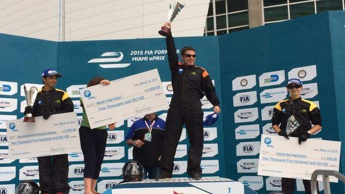 
Western High School driver Justyn Byrne (center) celebrates his win in Saturday’s Formula-e School Series race while runner-up Jonathan Morales (left) and third-place finisher Daniel Greenberg (right) look on. Prize money was awarded by Florida Power & Light to promote STEM education. 

