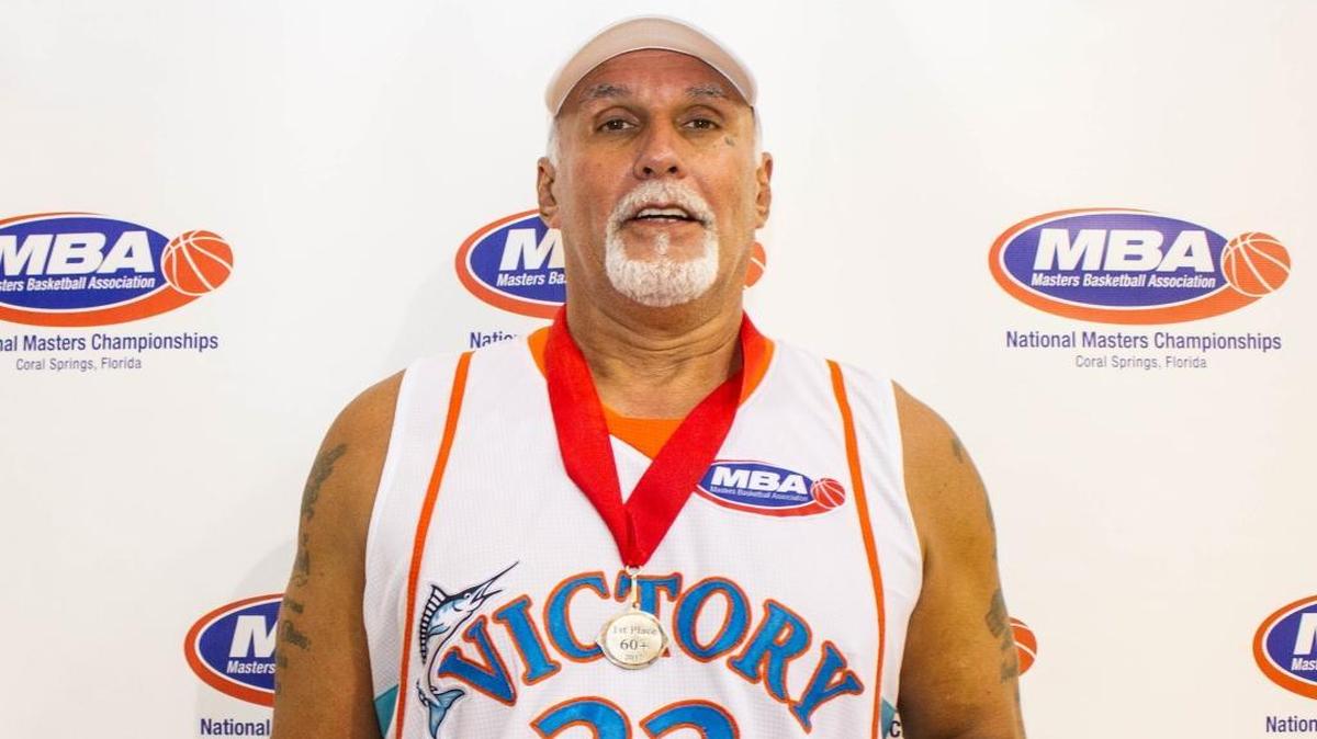 Julio Davila holds his Masters Basketball National Championships MVP ring and wears the team champ medal for the 60+ division.